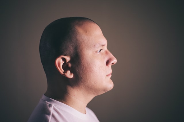 A closeup portrait of a man's one side face with bald head and clean shave