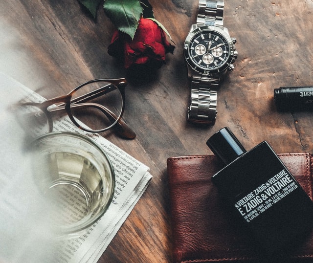 A classical image of a scents bottle beside watch, rose and eyeglass as advertising concept