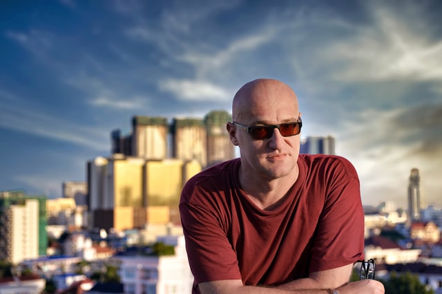 A portrait of a bald headed man wearing red t-shirt at outside
