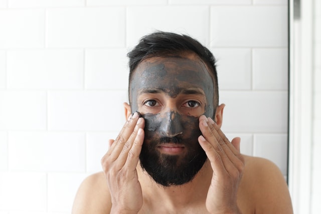 A man applying face mask on his face