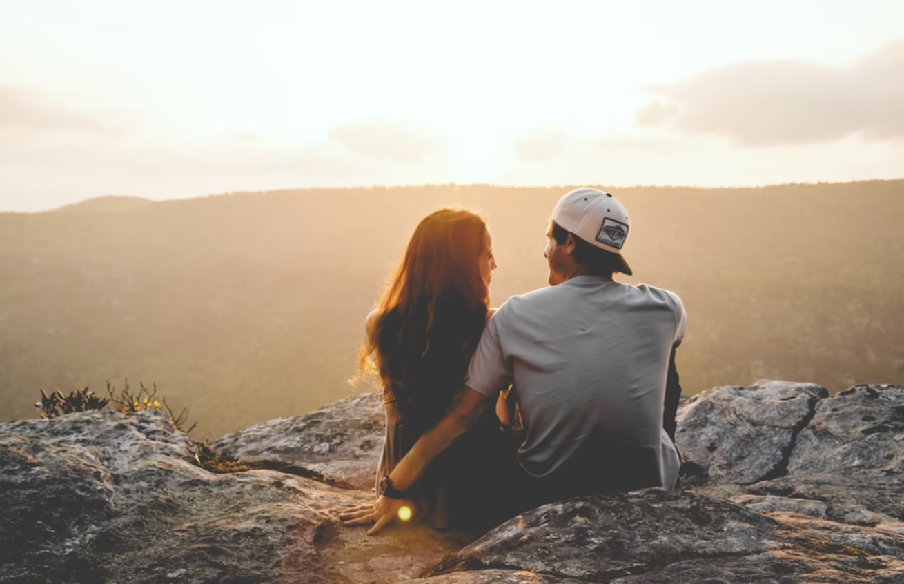 A picture of a couple seated on a hilltop