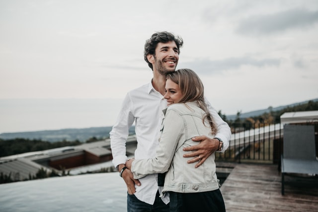 A joyful couple wearing white shirts hugged them while standing on a hillside