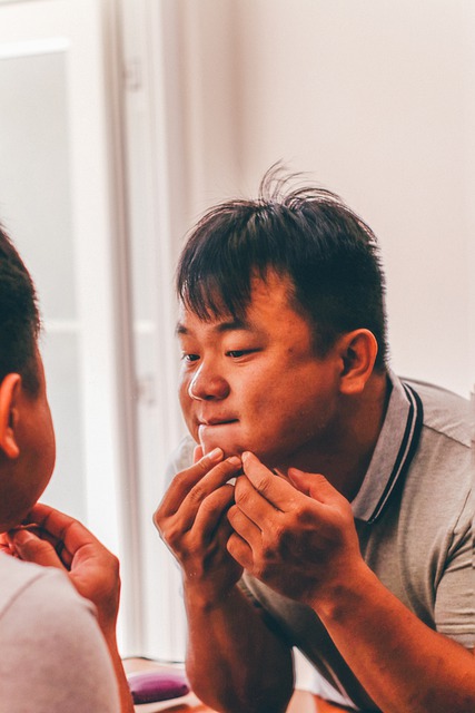 A man checking acne on his face looking at mirror