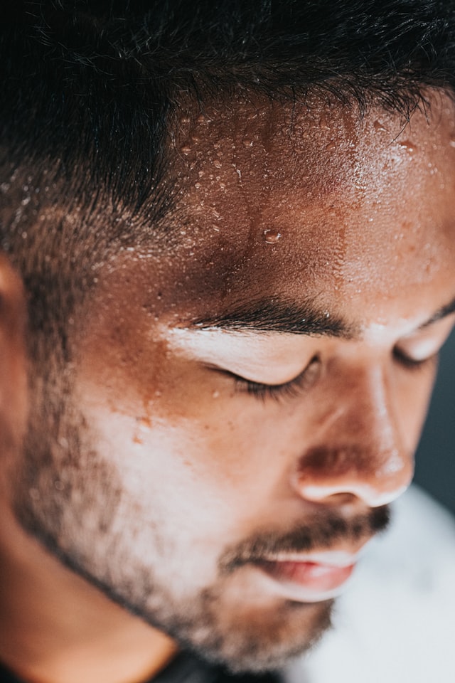 A closeup portrait of a man's sweating face 