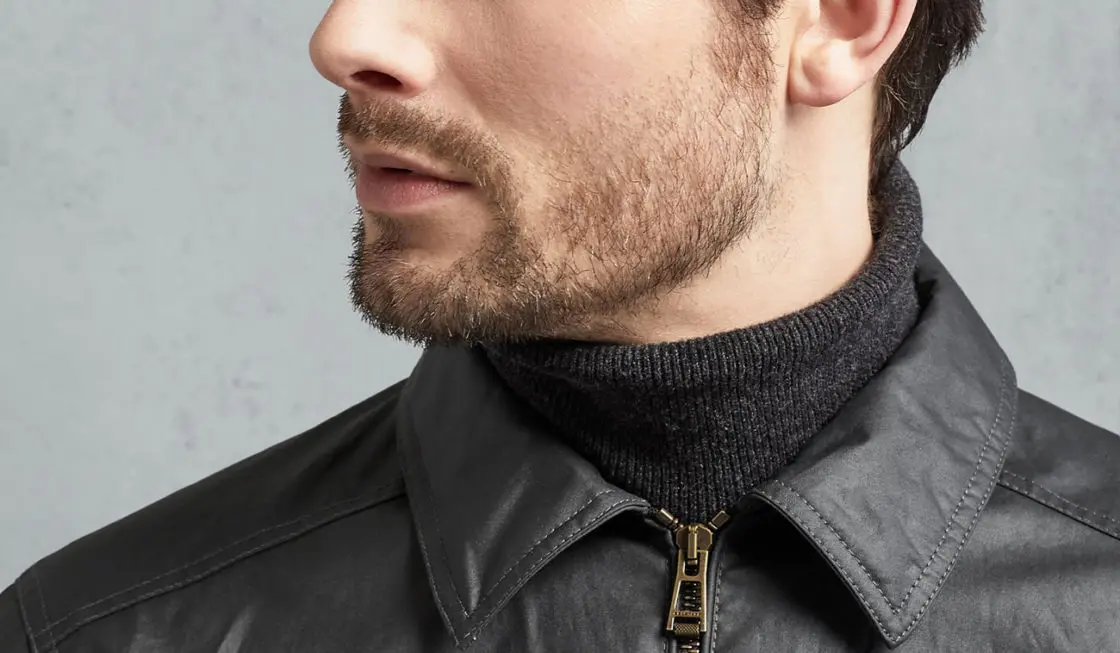 A closeup portrait of a man's half face with patchy beard
