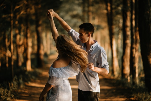A happy couple dancing on a forest road