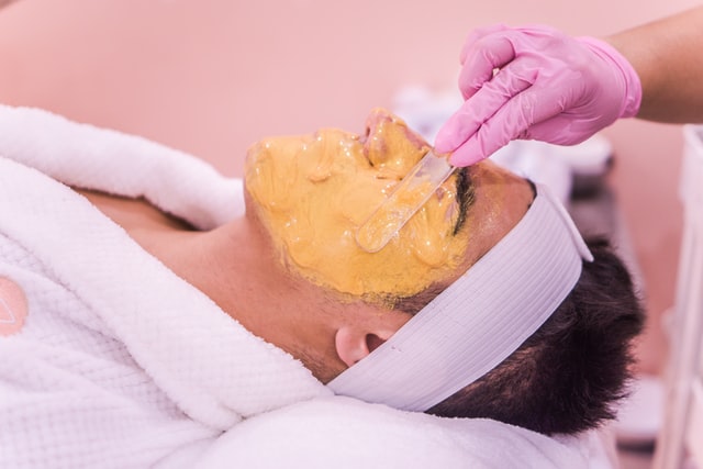 A closeup portrait of a man's face while using fascial scrub on his face at salon