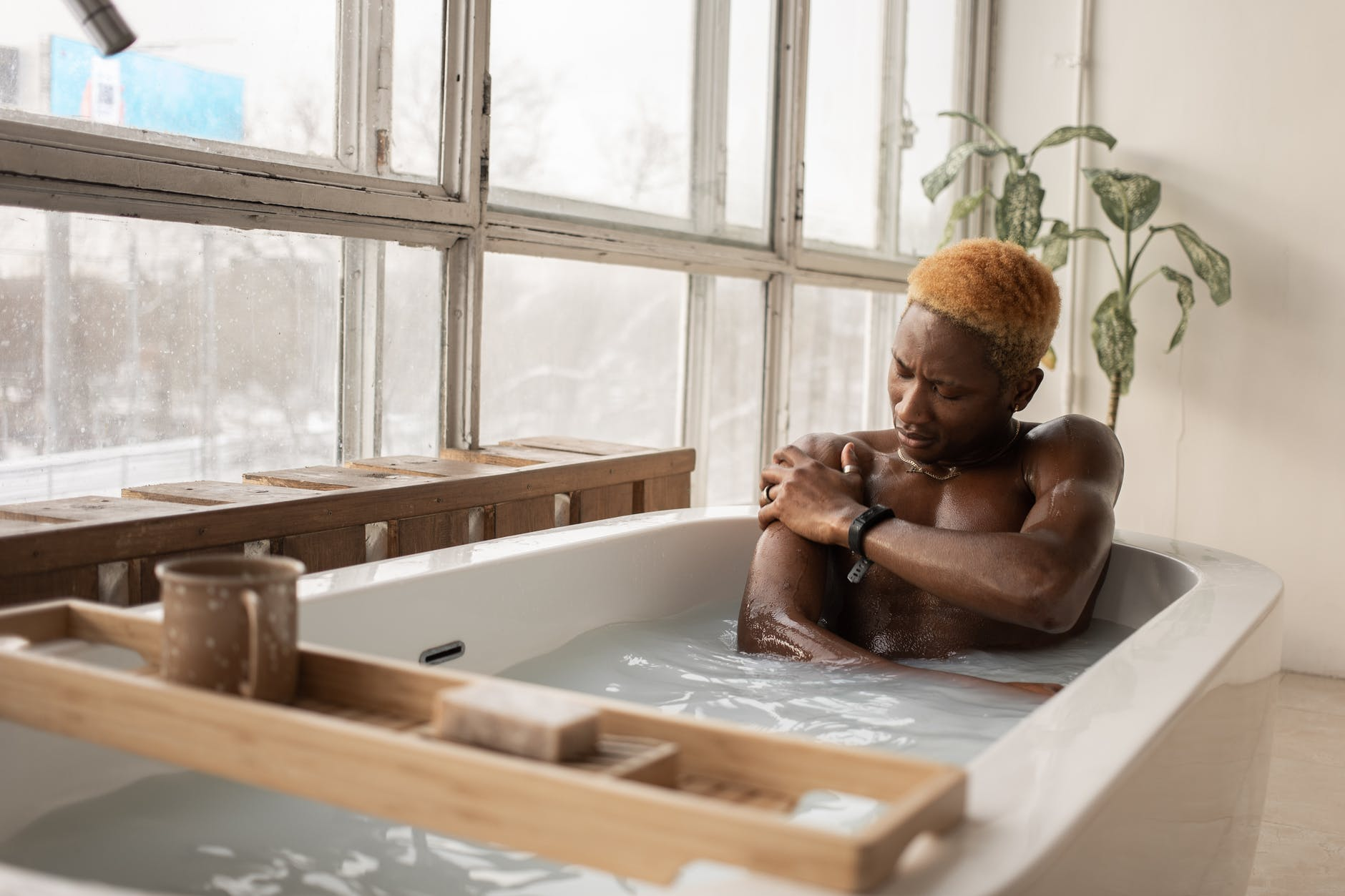 A black man washing his body while taking bath in a bathtub