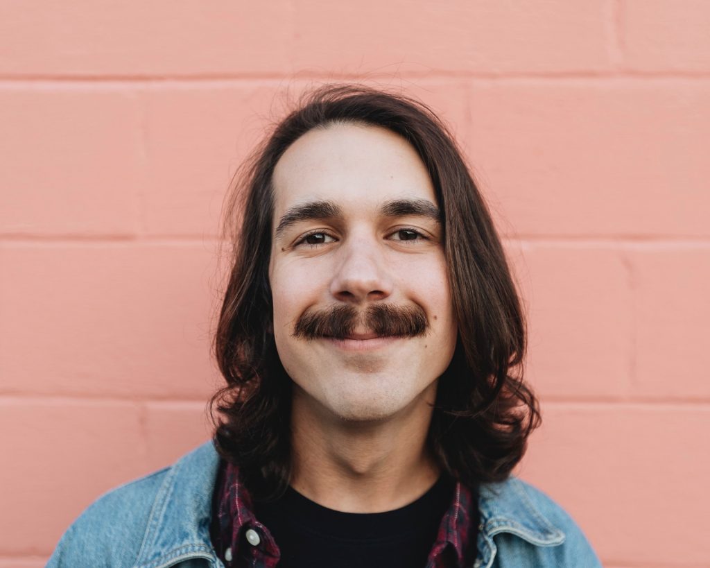 A portrait of well trimmed mustache man with long hair and clean shave look