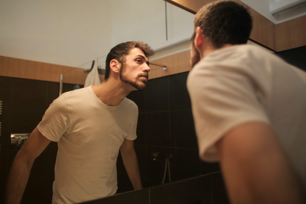 A man checking his beard cut looking into mirror 