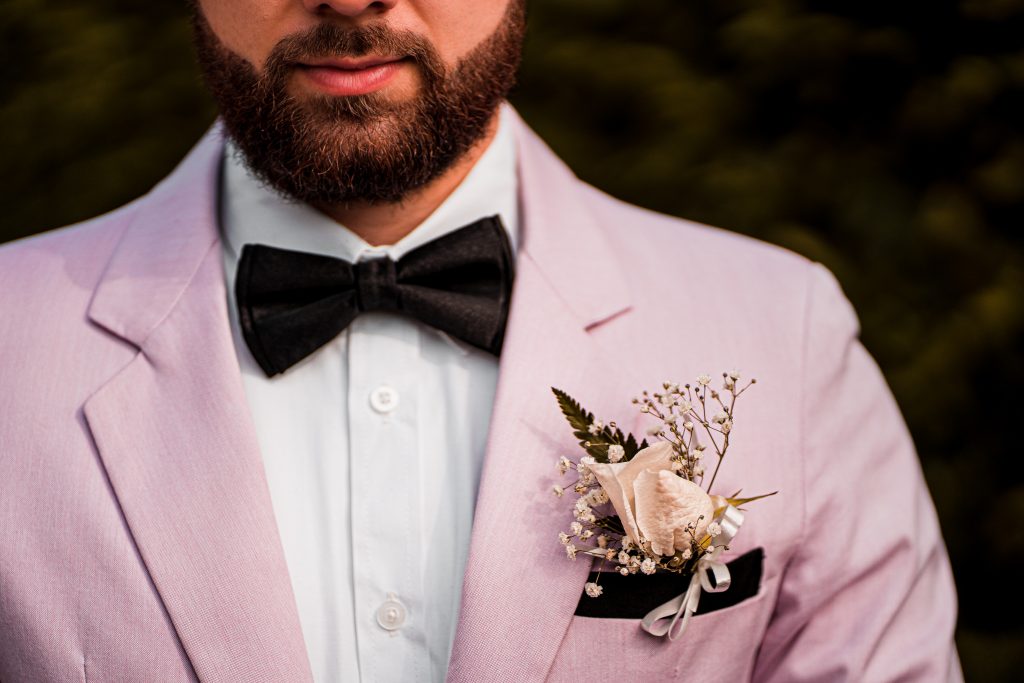 A closeup portrait of half of a man's face with nicely groomed beard wearing pink suit