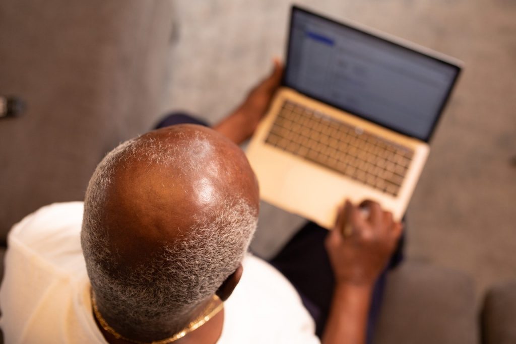 A bald headed man using laptop as an example image of baldness pattern in male