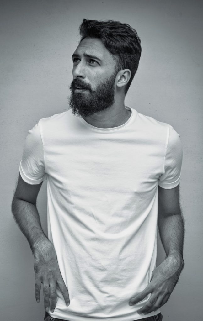 A portrait of a bearded man with white t-shirt