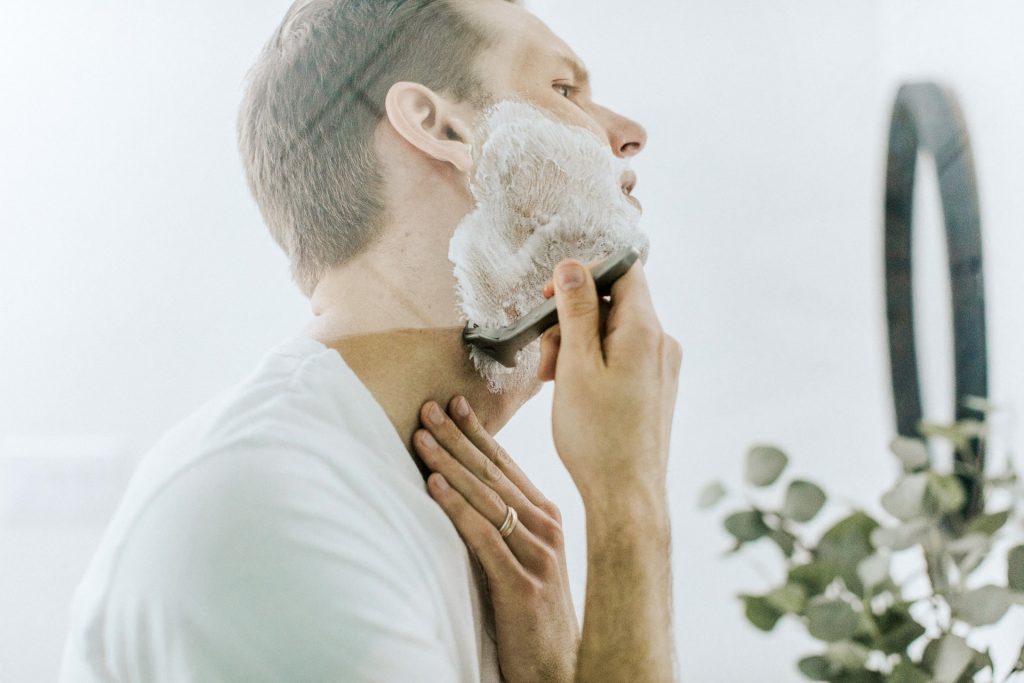 A closeup portrait of a man when he shaving his beard with razor