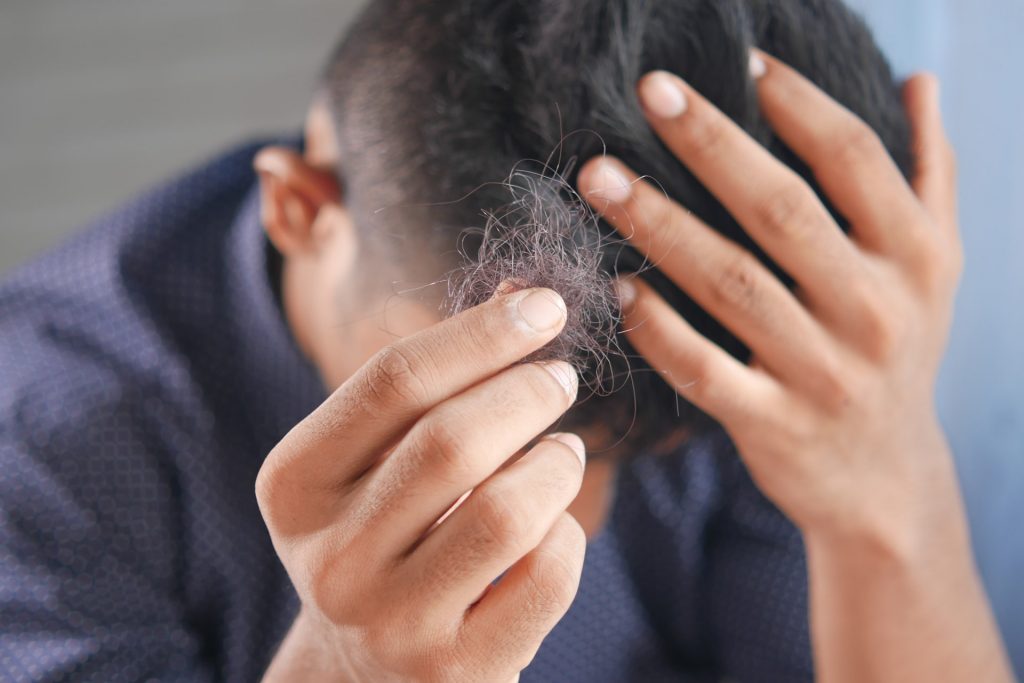 A man showing his fallen hair taking into hand after hair brushing