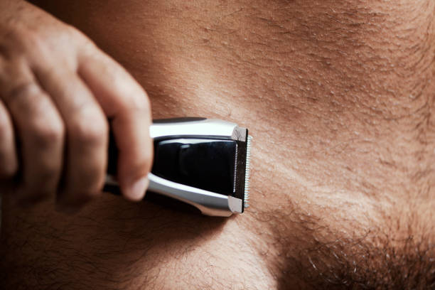 A man trimming the hair of his pubes with an electric trimmer